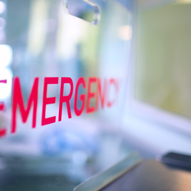 Transparent plastic divider on the reception desk in the hospital admission department with red lettering emergency.