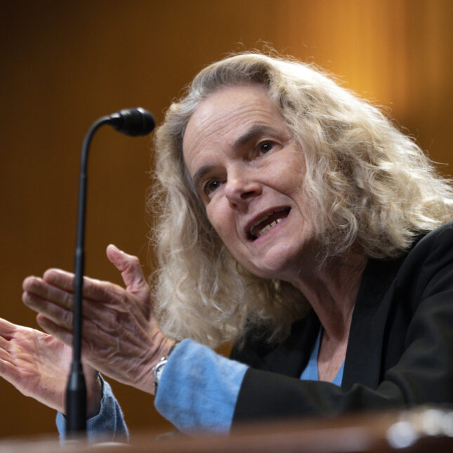 Nora Volkow faces both palms up while speaking – coverage from STAT