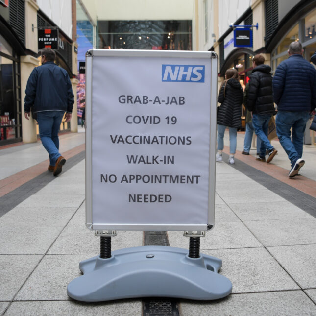 An NHS walk in vaccination sign int he middle of a mall. It reads "grab-a-jab covid-19 vaccinations walk-in no appointment needed."