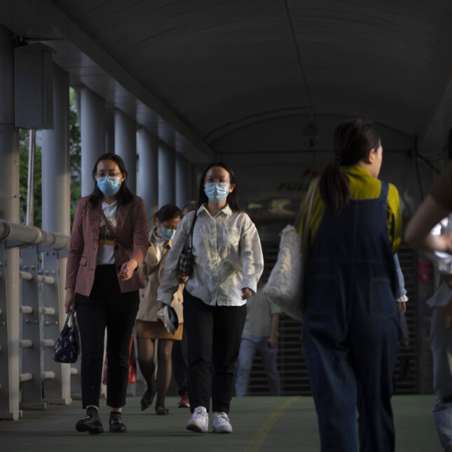 Commuters wearing face masks walk along a pedestrian bridge during the evening rush hour in Beijing -- health coverage from STAT